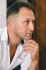 Fototapeta premium Indoor side-profile portrait of a thoughtful mature man, captured in soft natural light with a calm, reflective mood.