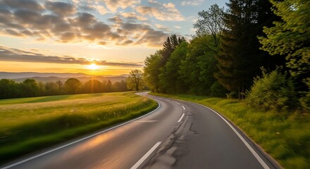 Fototapeta premium Scenic country road curves through green fields at sunrise.