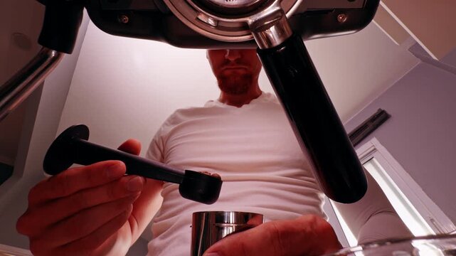 Bottom View of Man adding Coffee Bean into metal cup under Espresso Machine with Warm Light, Slow Motion showing preparation workflow