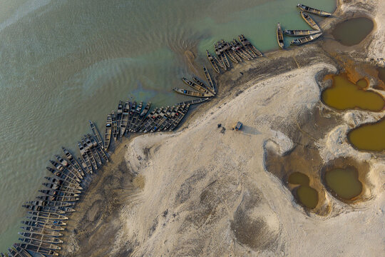 Aerial view of boats contrasting against the light sand and teal water, creating a mesmerizing scene, Tahirpur, Sylhet Division, Bangladesh.