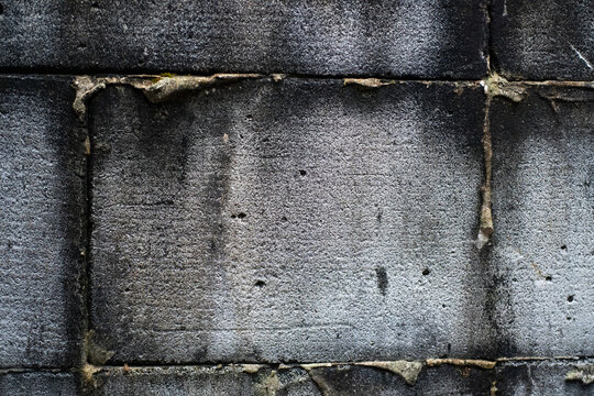 Close up of dark grey concrete blocks joined by messy mortar