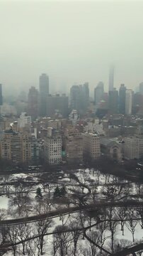 Sweep over Central Park winter snow paths with Manhattan skyline in dense fog