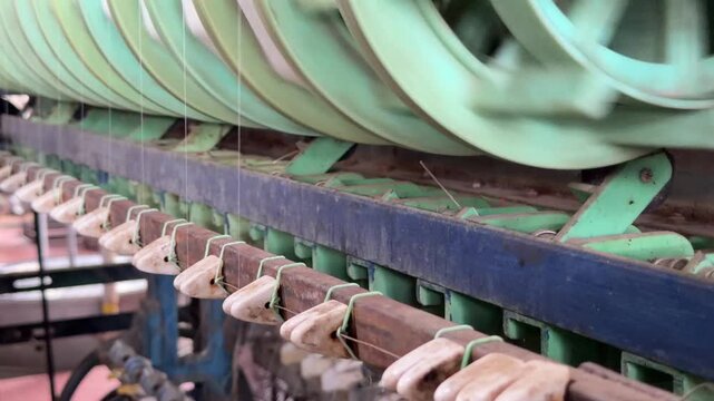 Industrial reels wind continuous silk filaments onto spools during cocoon processing, transforming natural fibers into usable textile material. Silk manufacturing.