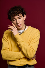 Stylish man exudes charm in vibrant attire against a rich backdrop of deep maroon