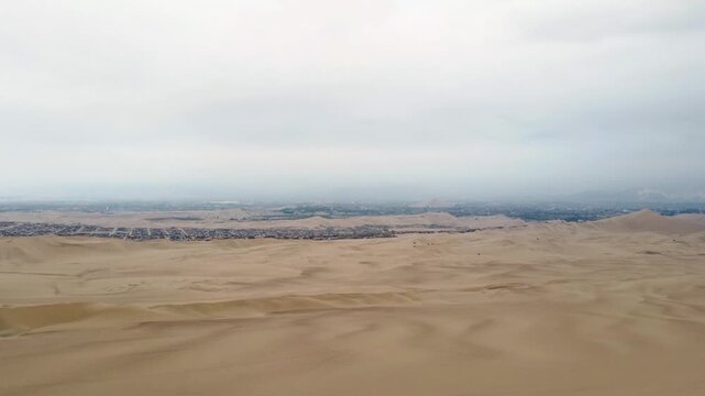 Aerial view drone Extraordinary dessert right behind the Oasis city in Huacachina, Ica, Peru cloudy day 4k