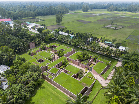 Gaibandha, Bangladesh - 21 June 2025: Aerial view of a unique architectural design with flat rooftops covered in green vegetation, nestled amidst lush greenery and open fields.