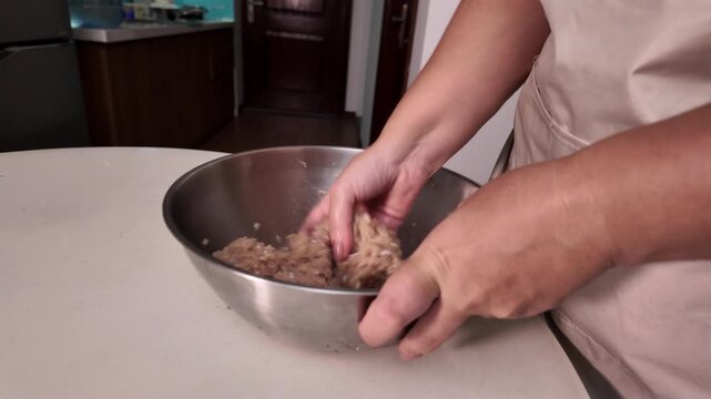 Female hands skillfully mix minced meat and finely chopped onion in a bowl