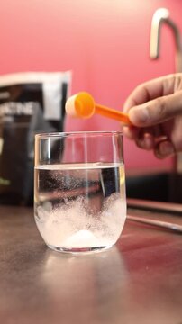 Person mixing creatine monohydrate powder supplement in a glass of water for muscle gain and athletic performance improvement