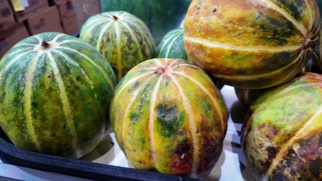 Close-up View of Freshly Harvested Striped Melons at a Local Market Stall.