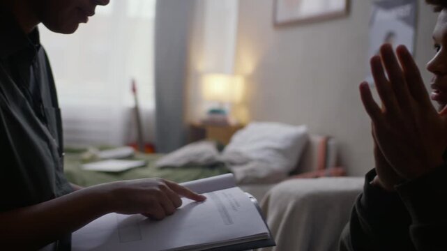 Slowmo shot of female social worker in uniform showing documents while interviewing vulnerable teenage African American boy, closing face with hands and avoiding eye contact during home visit