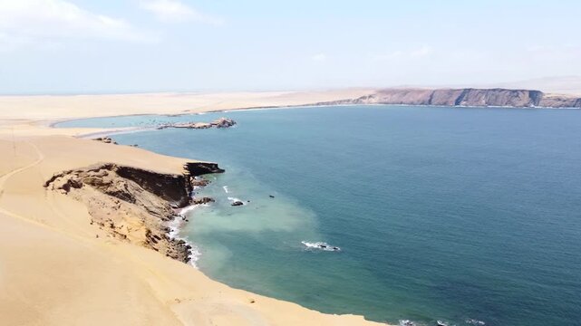 Drone aerial view, red sand beach, big waves and road in desert cliff blue sea clear sky blue. Paracas National Park, Peru 4k
