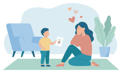 Little boy gives his mother a handmade drawing, making her feel emotional and loved as she sits on the floor covering her face with joy in a cozy living room