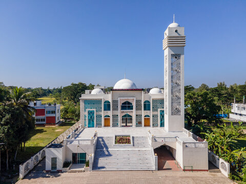 Chattogram, Bangladesh - 30 November 2023: Aerial view of the Baitus Salam Jame Masjid stands tall, its white facade and minaret contrasting with the surrounding greenery.
