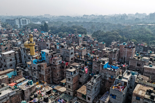 Aerial view of densely packed buildings, with a prominent mosque minaret piercing the skyline, a stark contrast to the distant hazy horizon, Dhaka, Dhaka Division, Bangladesh.