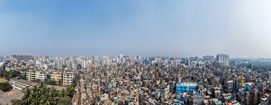 Aerial view of a densely packed urban landscape, where tightly clustered buildings contrast with the modern high-rises in the background, Dhaka, Bangladesh.