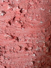 Fototapeta premium Close-up view of a heavily textured pink painted surface showing dramatic peeling and weathered layers