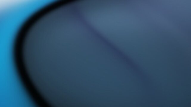 Close-up view of a blurred abstract blue metal surface with curved dark line dividing light and shadow tones