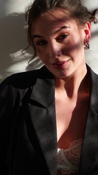 A portrait of a lady gazing into the lens, clad in a chic jacket, with light streaming in through the windows.
