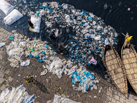 Aerial view of the Buriganga River choked with an appalling amount of discarded waste, contrasting with the traditional wooden boats, Dhaka, Dhaka Division, Bangladesh.