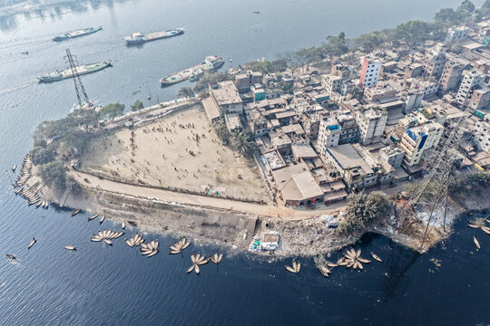 Aerial view of boats clustered along the murky riverbank near a densely packed settlement, Dhaka, Dhaka Division, Bangladesh.