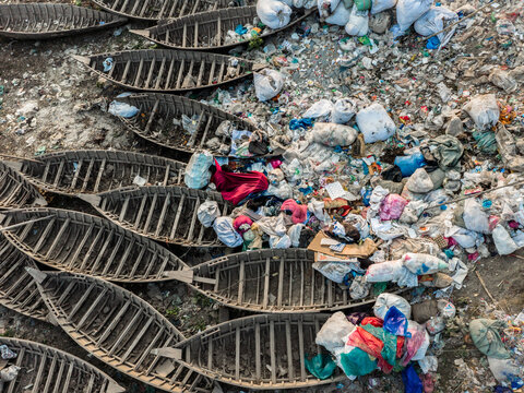 Aerial view of a stark contrast between traditional wooden boats and heaps of discarded plastic waste along the Buriganga River, Dhaka, Dhaka Division, Bangladesh.