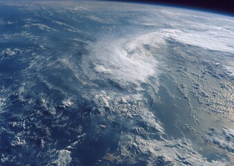 Aerial view of a large swirling storm system over ocean waters and land. Clouds dominate the landscape
