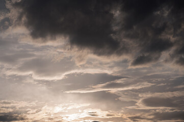 Obraz premium Dramatic sunset sky with dark storm clouds and soft light, moody atmosphere before rainfall