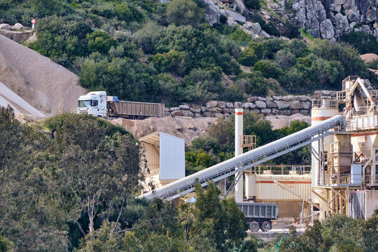 Manilva, Spain - 18 February 2026: View of heavy machinery and trucks amidst a landscape of contrasting textures and tones at the quarry site.