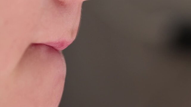 Extreme macro close-up of a young boy's lips pursing and compressing in a side profile. 