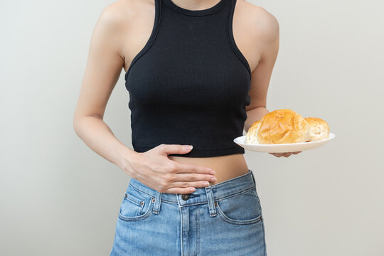 Gluten allergy, asian young woman hand holding, refusing to eat white loaf slice on plate in breakfast food meal at home, girl having a stomach ache. Gluten intolerant and Gluten free diet concept.