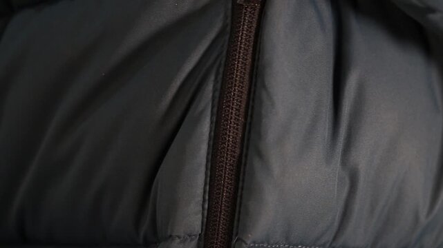 Extreme macro close-up of a person zipping up a warm winter jacket.