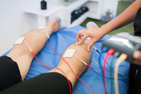 Patient's legs with electrodes and cables during a physiotherapy session