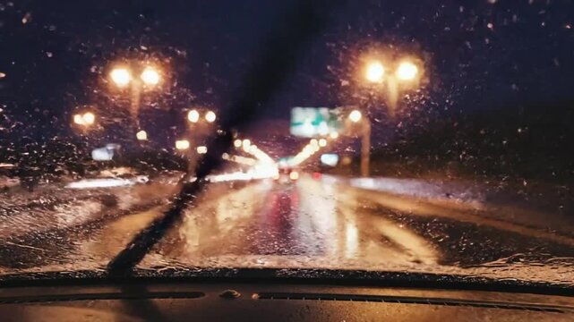 Driving Through a Wet Road at Night with Street Lights and Raindrops on the Windshield