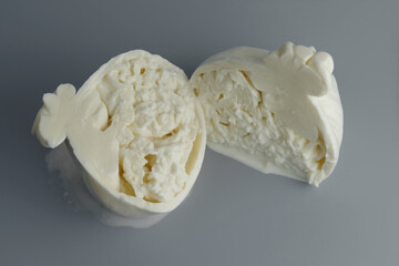Sliced head of typical Italian cow milk cheese Burrata on a grey background.