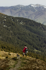Fototapeta premium Young woman standing on rocky mountain summit overlooking vast valley and clouds. Travel adventure and hiking lifestyle concept, freedom, exploration and inspiration in scenic wilderness panorama