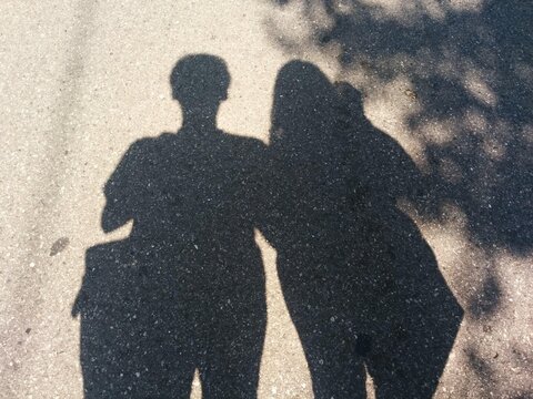 Shadow of a Man and a Woman Cast on Asphalt Surface in Bright Sunlight