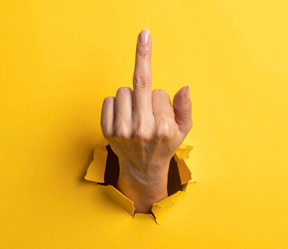 Hand hält den Mittelfinger hoch vor einem Loch auf gelbem Hintergrund