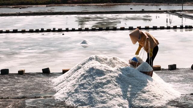 Vietnam worker carrying salt in baskets from salt fields near nha trang, vietnam, at the hon khoi