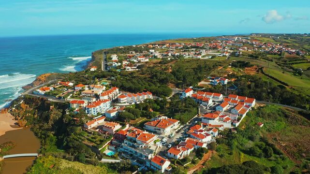 Aerial view of a small European town against blue sky and Atlantic Ocean. Drone view of a beautiful European city with a beautiful hilly landscape on ocean background.  Cinematic   footage. Portugal.