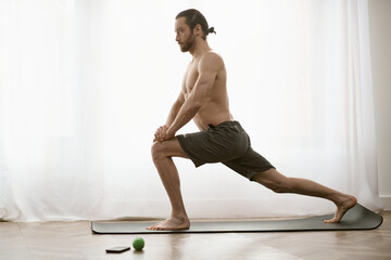 Obraz premium Handsome man practicing yoga at home in a peaceful and inviting space