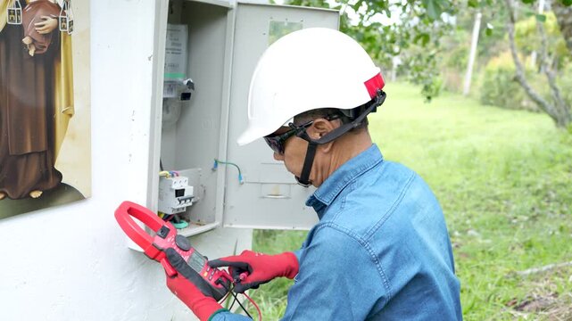 Professional electrician using a clamp meter to measure the flow of electric current