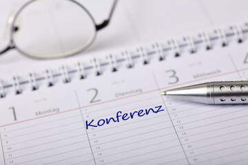Calendar with noted conference and a pen on a table