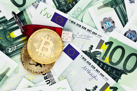 Two Bitcoin coins and USB flash drive on the background of euro banknotes
