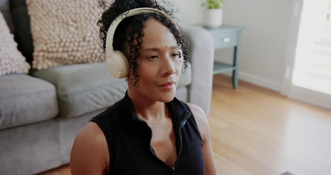 African adult woman sitting at home following guided audio with headphones forming mudra meditating