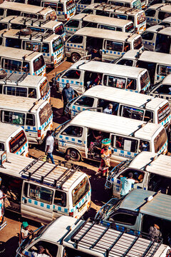 Kampala, Uganda - 28 March 2024: View of a sea of white and blue minibuses, a vibrant tapestry of urban transport, bustling with people navigating the crowded streets.
