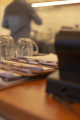 Obraz premium Restaurant station with organized cutlery. Efficient pass counter with neatly arranged utensils. Orderly restaurant interior with prepared cutlery and warm lighting ambiance