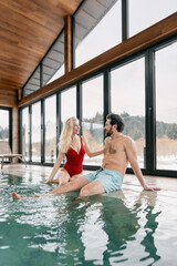 Couple enjoying a relaxing winter spa day in a luxurious indoor swimming pool