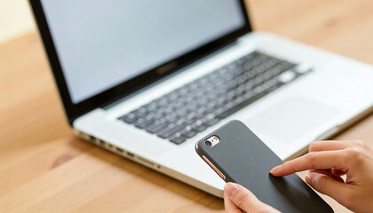 Fototapeta premium Close-up of hands using smartphone and laptop on wooden desk, modern technology and remote work concept