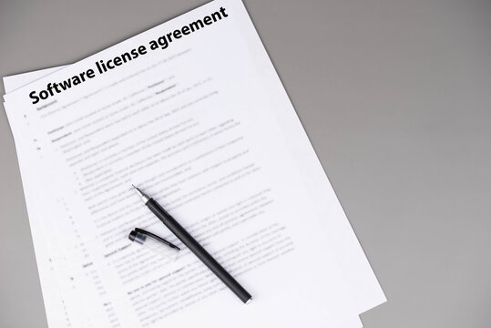 Software license agreement document on office desk, legal contract granting rights to use software under specific terms, symbol of digital compliance, intellectual property, and business technology.