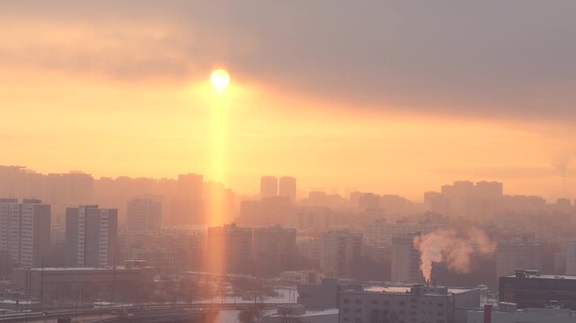 Rare atmospheric light pillar phenomenon above urban skyline during freezing winter sunrise with dramatic golden light and icy air conditions